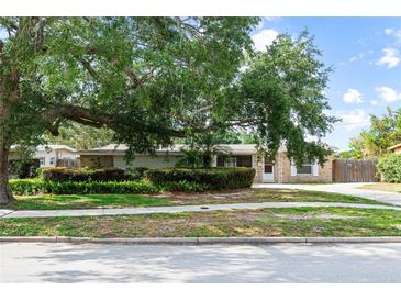 Single story brick home with well maintained landscaping and a large shade tree in the front yard at 4021 Hargill Dr, Orlando, FL 32806