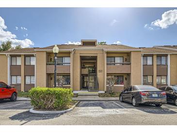 Condo exterior shows the building facade, parking and landscaping under a bright, sunny sky at 5321 Vineland Rd # 101, Orlando, FL 32811