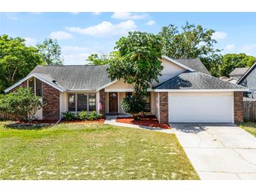 Charming single-story home features a brick accent, manicured lawn, and an attached two-car garage at 8004 Village Green Rd, Orlando, FL 32818