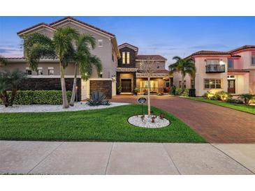 Elegant two-story home featuring lush landscaping, a brick driveway, and a classic Mediterranean-style tile roof at 10196 Bucklow Hill Dr, Orlando, FL 32832