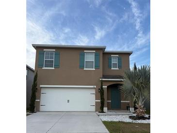 Two-story home with a two car garage, green shutters, and landscaping at 321 Jovana Rd, Davenport, FL 33837