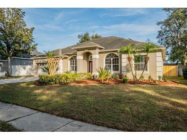Well-manicured lawn leads to a single-story home with arched windows and a neutral color palette at 4837 Lorraine Way, Orlando, FL 32812
