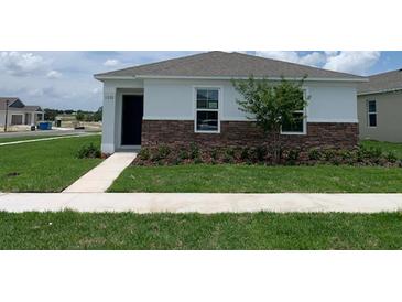 Charming single-Gathering home featuring stone accents, a well-manicured lawn, and a neatly landscaped front yard at 5290 Scrub Mint Ln, Apopka, FL 32712