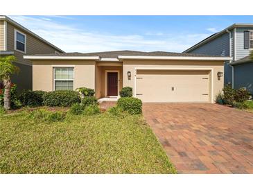 Charming single-story home featuring a two-car garage and brick paved driveway at 714 Golden Elm Dr, Apopka, FL 32703