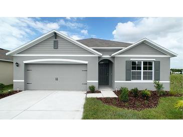 Charming gray single-Gathering home boasts a well-manicured lawn and a two car garage at 943 Princess Sabal Pt, Haines City, FL 33844