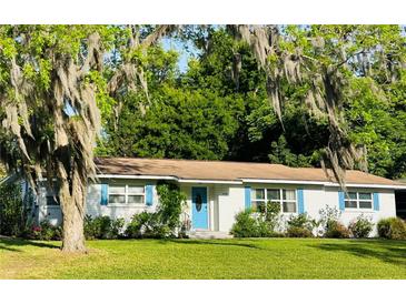 Charming one-story home featuring a well-manicured lawn, blue shutters, and a bright blue front door at 1118 Ne 17Th Ave, Ocala, FL 34470