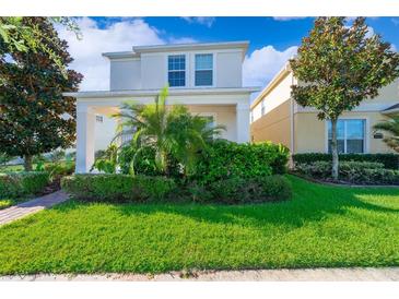 Well-maintained front yard with lush green lawn, colorful bushes and landscaped garden beds at this lovely two-story home at 11386 Biography Way, Orlando, FL 32832