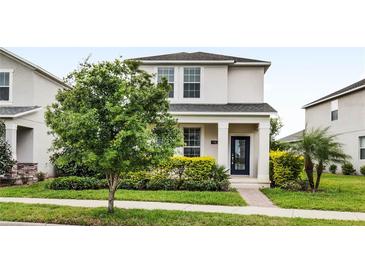 Charming two-story home features a well-manicured lawn and colorful landscaping at 11386 Biography Way, Orlando, FL 32832