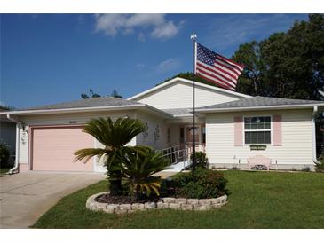 Charming single-story home with a well-manicured lawn and a lovely garden bed featuring tropical plants at 32900 Crooked Oaks Ln, Leesburg, FL 34748