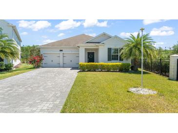 Charming one-story home featuring a well-manicured lawn, a paver driveway, and an attached two-car garage at 4599 Storytelling Way, Kissimmee, FL 34746