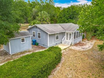 Charming one-story home featuring light blue siding, a screened porch, and a lush, green hedge at 499 W Beresford Rd, Deland, FL 32720