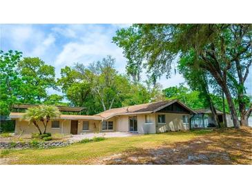 Sprawling single-story home with mature trees, a covered patio, and a well-manicured lawn, offering a serene outdoor experience at 530 Webster St, Lake Mary, FL 32746