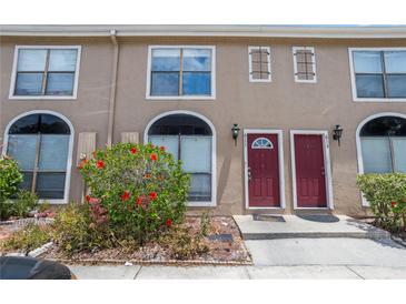 Charming townhome exterior with red doors, blooming hibiscus, and well-maintained landscaping at 611 Casa Park A Ct, Winter Springs, FL 32708