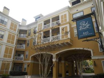 Exterior shot of a multi-story tan building with balconies and covered parking at Park North at Cheney Place at 860 N Orange Ave # 428, Orlando, FL 32801