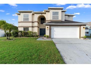 Two-story home featuring a well-manicured lawn, a two-car garage, and a neutral-colored facade at 12543 Waterhaven Cir, Orlando, FL 32828