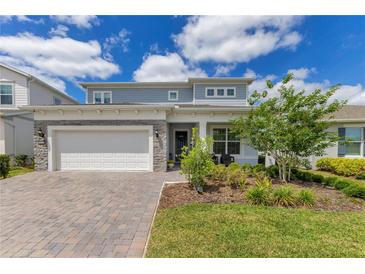 Charming two-story home with a brick driveway, well-manicured lawn and stone veneer details at 13330 Panama Beach Ct, Orlando, FL 32827