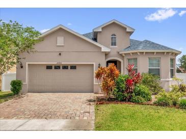 Charming home featuring a two-car garage, brick driveway, and lush landscaping at 16780 Meadows St, Clermont, FL 34714