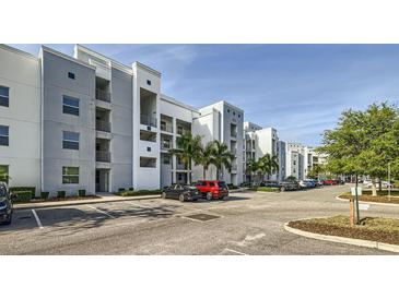 Modern condo building with ample parking, palm trees, and well-maintained landscaping under a bright sky at 4731 Clock Tower Dr # 104, Kissimmee, FL 34746