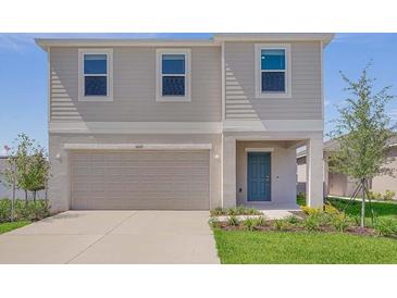 Charming two-story home featuring a tidy lawn, an attached two-car garage, and a welcoming blue front door at 5109 Forget Me Not Ave, Lake Hamilton, FL 33851