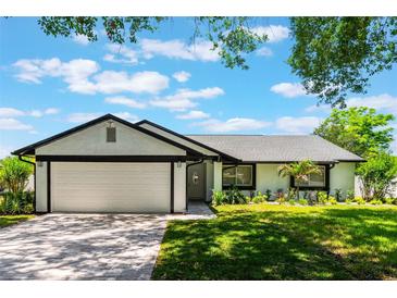 Charming single-story home with a lush lawn, brick driveway, and attached two-car garage at 7664 Clubhouse Estates Dr, Orlando, FL 32819