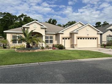 Charming single-story home featuring stucco siding, a manicured lawn, and a well-maintained three car garage at 11120 Se 168Th Loop, Summerfield, FL 34491