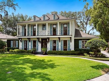 Stunning two-story home featuring a lush green lawn, elegant shutters, and charming balconies at 1400 Place Picardy, Winter Park, FL 32789
