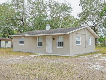 Modest single-story home with neutral paint, simple landscaping, and mature trees in the front yard at 1708 Nebraska Ave, Kissimmee, FL 34744