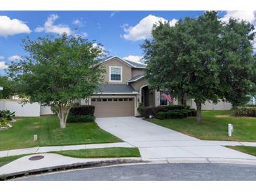 Charming two-story home with a manicured front yard, mature trees, and a two-car garage, offering classic curb appeal at 23520 San Sebastian Ct, Sorrento, FL 32776