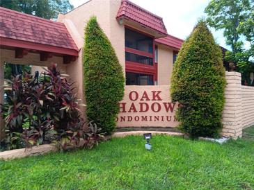 Inviting Oak Shadows Condominium signage with lush landscaping and well maintained grounds at 2810 N Powers Dr # 59, Orlando, FL 32818