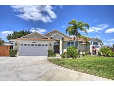 Beautiful one-story home with a well-manicured lawn, lush landscaping, and a two-car garage on a sunny day at 2850 Babylon Ct, Oviedo, FL 32765