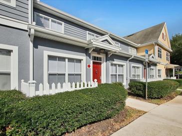 Charming townhome featuring a red front door, and meticulously maintained landscaping at 4560 Spigold Court, Kissimmee, FL 34746