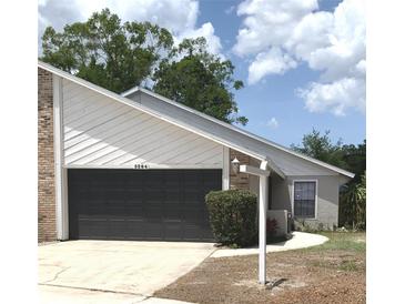 Traditional home exterior featuring a two-car garage, well-kept lawn, and attractive landscaping at 5284 Indian Laurel Ct, Orlando, FL 32808