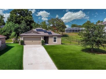 Charming one-story home features a well-maintained lawn, a two-car garage, and solar panels at 543 Nardello Dr, Deltona, FL 32725