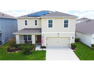 Charming two-story home with a manicured lawn, two-car garage, and modern solar panels at 9040 Alba Ln, Kissimmee, FL 34747