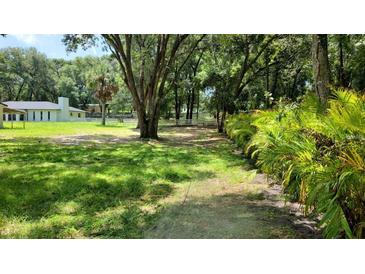 Sprawling grassy yard with mature trees and white fencing surround this beautiful country property at 16742 Se 165Th Ave, Weirsdale, FL 32195