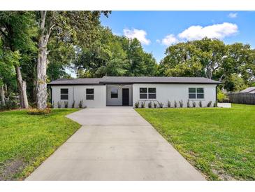Charming single-story home featuring a well-maintained front yard and a long concrete driveway at 50 Community Dr, Debary, FL 32713