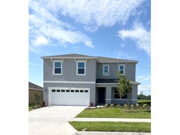 Two-story home with a gray facade, well-manicured lawn, and a two-car garage at 5168 Greenheart Ave, Mount Dora, FL 32757