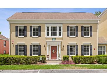 Two-story tan home with black shutters, red door, manicured landscaping, and an inviting entrance at 754 Centervale Dr, Kissimmee, FL 34747