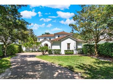 Beautiful two-story home with a well manicured lawn, lush landscaping, and brick paved driveway at 9743 Covent Garden Dr, Orlando, FL 32827