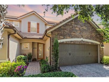Charming home showcasing stone accents, a two-car garage, and a beautifully landscaped front yard at 10533 Belfry Cir, Orlando, FL 32832