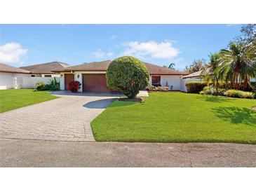 Charming single-story home with a well-manicured lawn, brick driveway, and an attached two-car garage at 21 Abbey Ct, Haines City, FL 33844