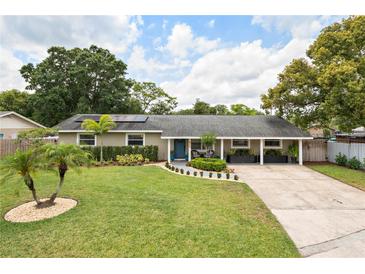Charming single-story home featuring a well-manicured lawn and a welcoming front porch with blue door at 417 Carvell Dr, Winter Park, FL 32792