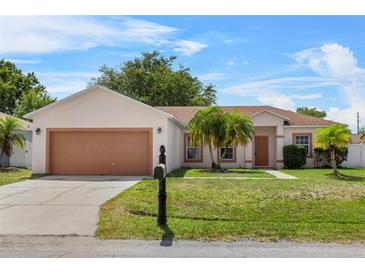 Charming single-story home with a well-maintained lawn, lovely palm trees, and two-car garage at 504 Delido Way, Kissimmee, FL 34758