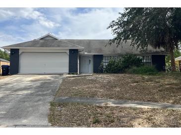 Cozy single-story home with a white garage door, dark siding accents, and a spacious front yard at 7614 Brisbane Ct, Orlando, FL 32835