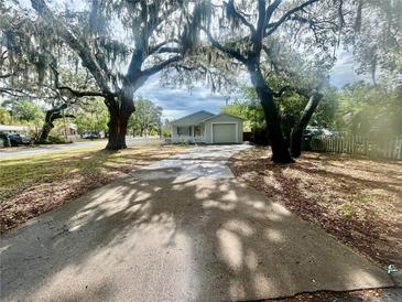 Charming home featuring mature trees, a driveway, and a white picket fence at 1040 N Clayton St, Mount Dora, FL 32757