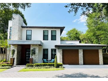 Modern two-story home showcasing stone accents, a two-car garage, and manicured landscaping at 1831 Mizell Ave, Winter Park, FL 32789