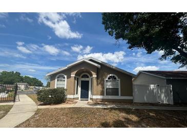 Inviting single-story home with a blue door and arched windows, set under a bright blue sky at 410 Horizon Dr, Winter Springs, FL 32708