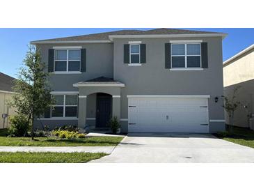 Two-story home featuring a two-car garage, well-manicured lawn, and freshly painted exterior with stylish shutters at 919 Princess Sabal Pt, Haines City, FL 33844