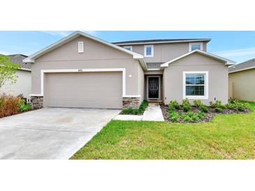 Charming two-story home featuring a well-manicured lawn, a stone-accented facade, and a two-car garage at 4792 Vellacito Way, Davenport, FL 33897