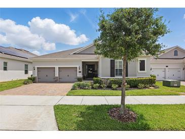 Charming single-story home featuring a brick driveway, two-car garage, and well-maintained landscaping at 5427 Orange Orchard Dr, Winter Garden, FL 34787